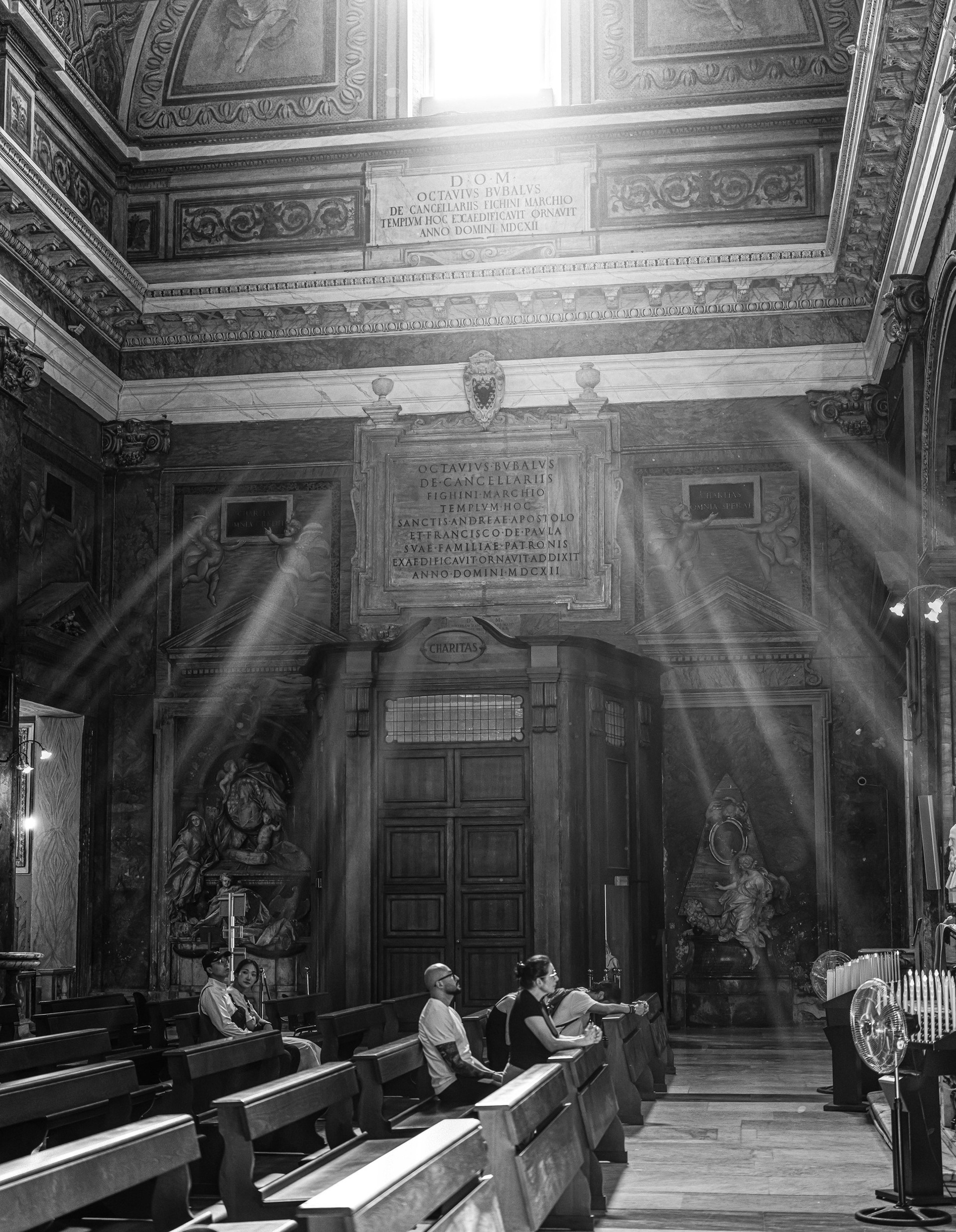 Charitas: raggi di luce nella navata di Sant'Andrea delle Fratte a Roma con due persone sedute, fotografia in bianco e nero di Fabio Alimonti