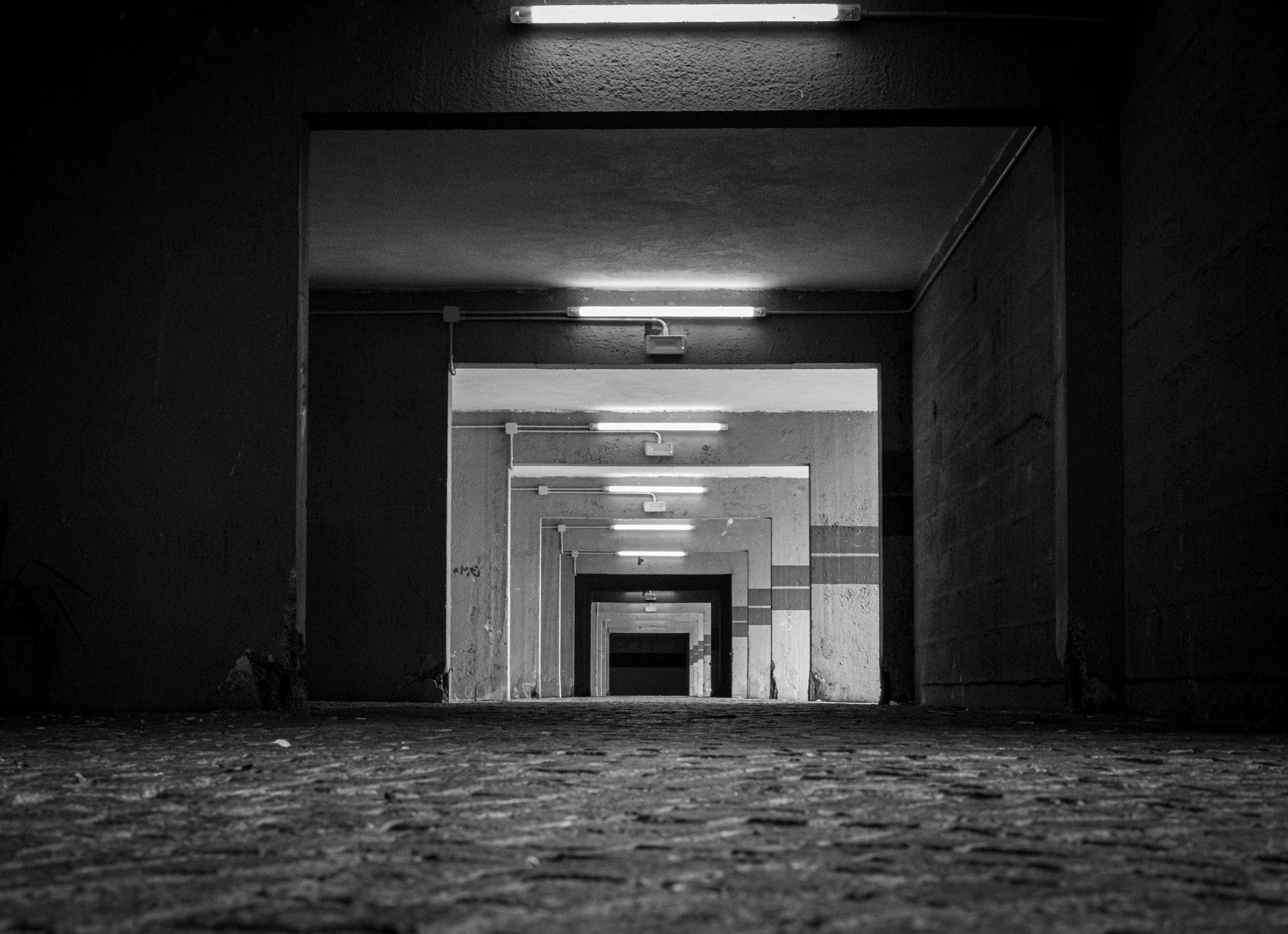 A un passo dal buio — corridoio di cemento con neon, aperture una dentro l’altra, Corviale, Roma, bianco e nero, Fabio Alimonti