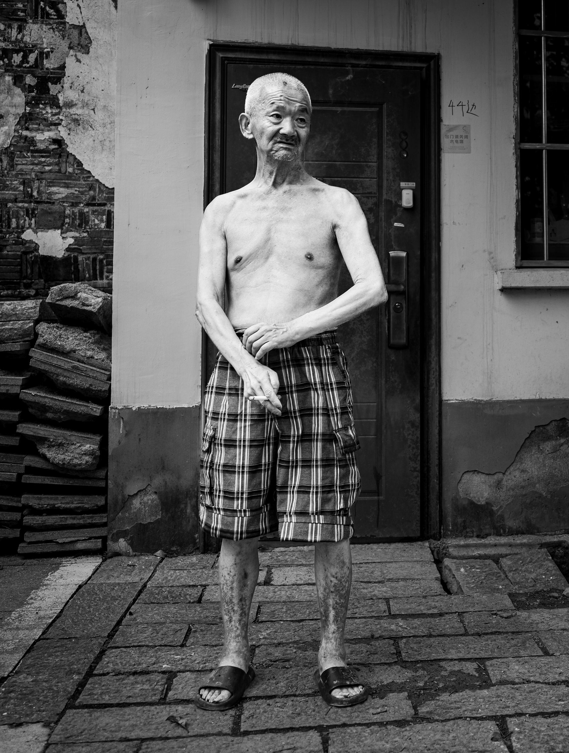 44 – anziano a torso nudo sulla soglia di casa, Suzhou, Cina. Fotografia in bianco e nero di Fabio Alimonti