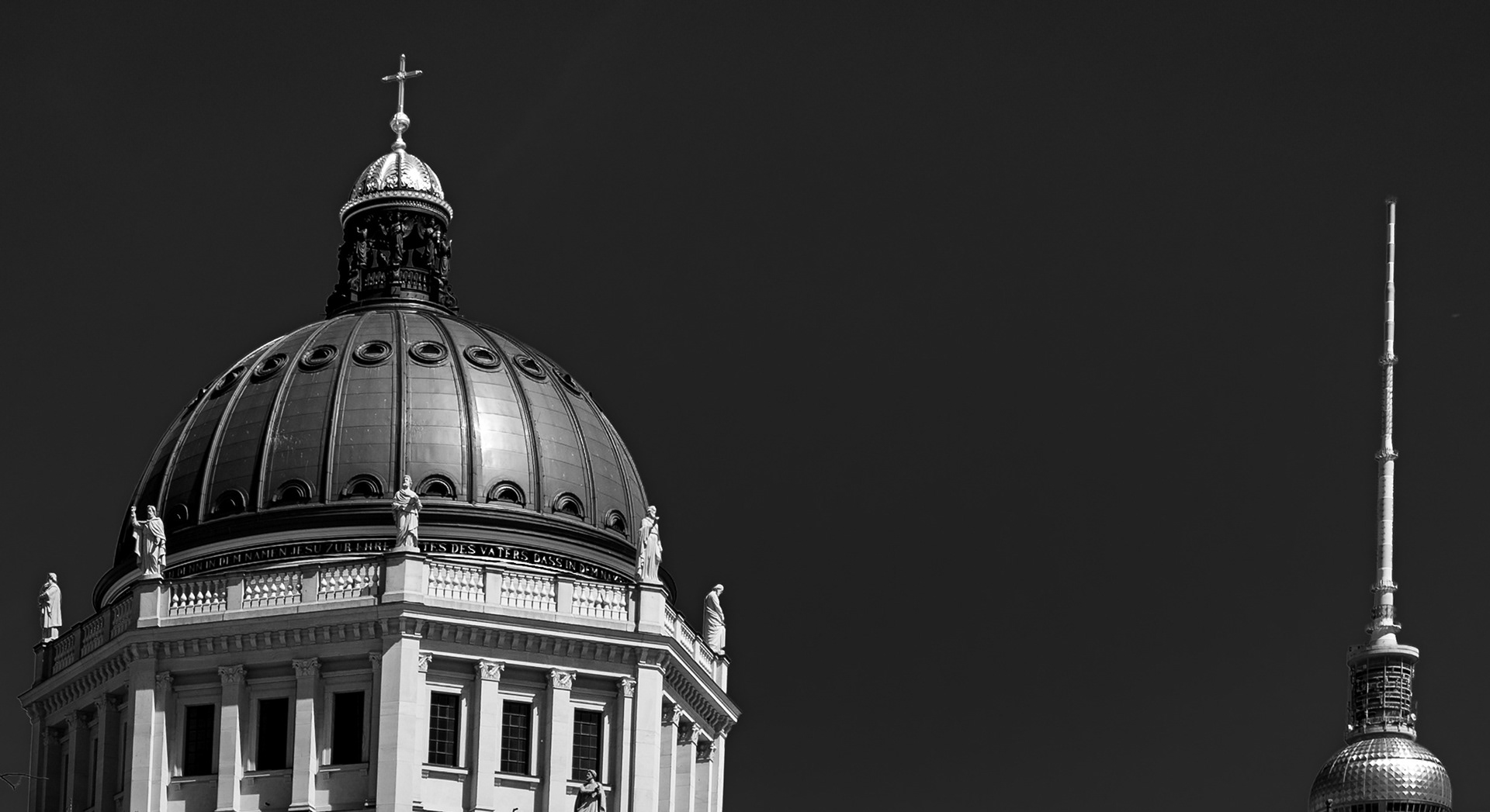 Due altezze – la cupola del Humboldt Forum con la croce e, a destra, la torre della televisione di Berlino, separate da un cielo scuro. Fotografia in bianco e nero di Fabio Alimonti.