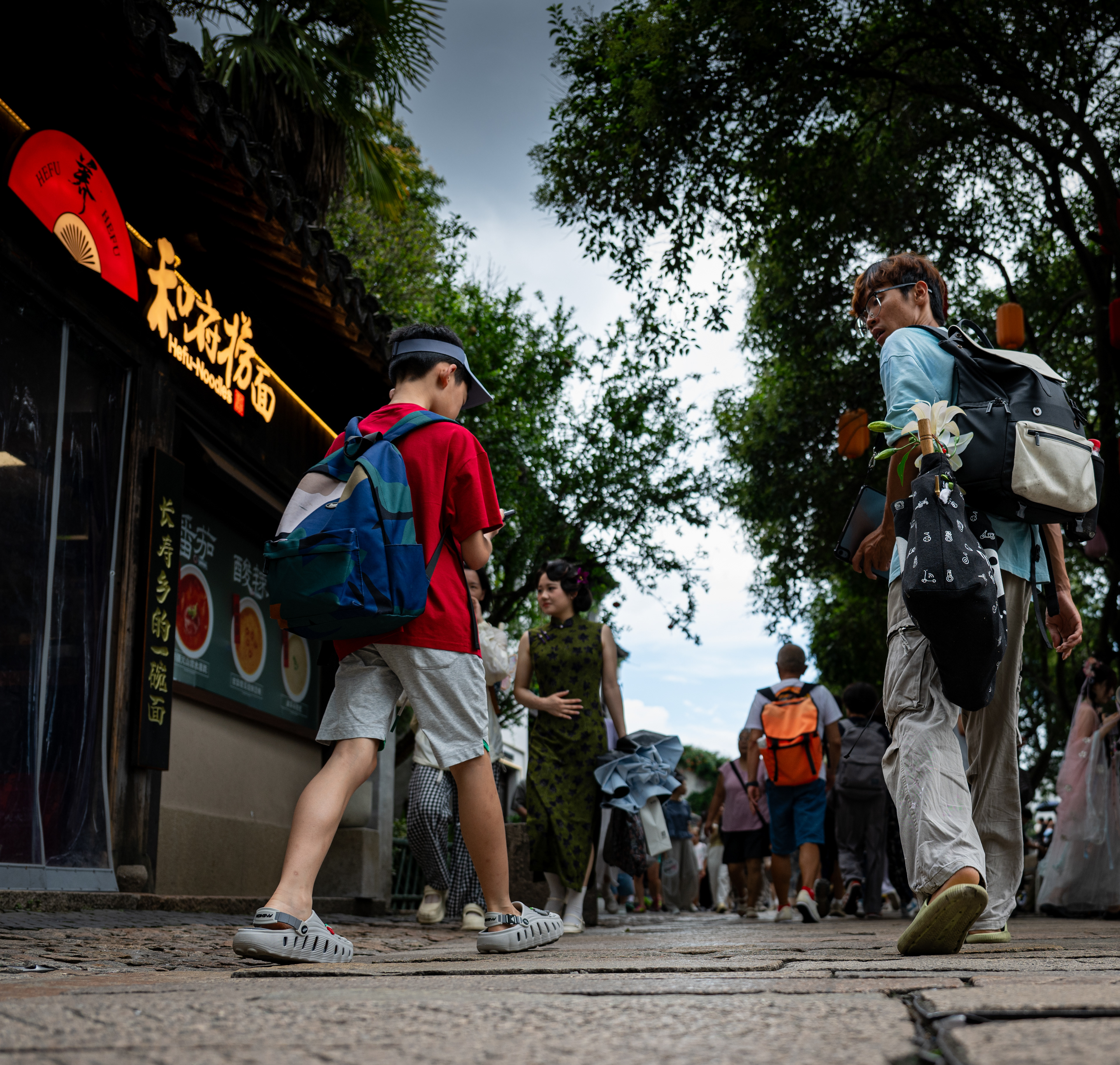 Un passo avanti – padre e figlio in una via di Suzhou, Cina, il ragazzo guarda il telefono – fotografia di Fabio Alimonti