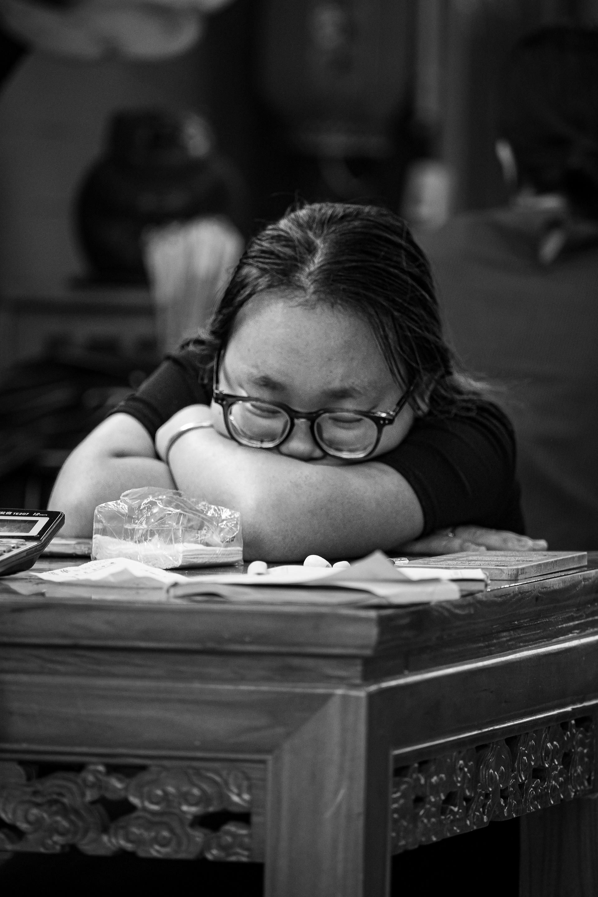 Ora di riposo: ragazza addormentata dietro il banco di un negozio a Pingyao, Cina, bianco e nero, fotografia di Fabio Alimonti