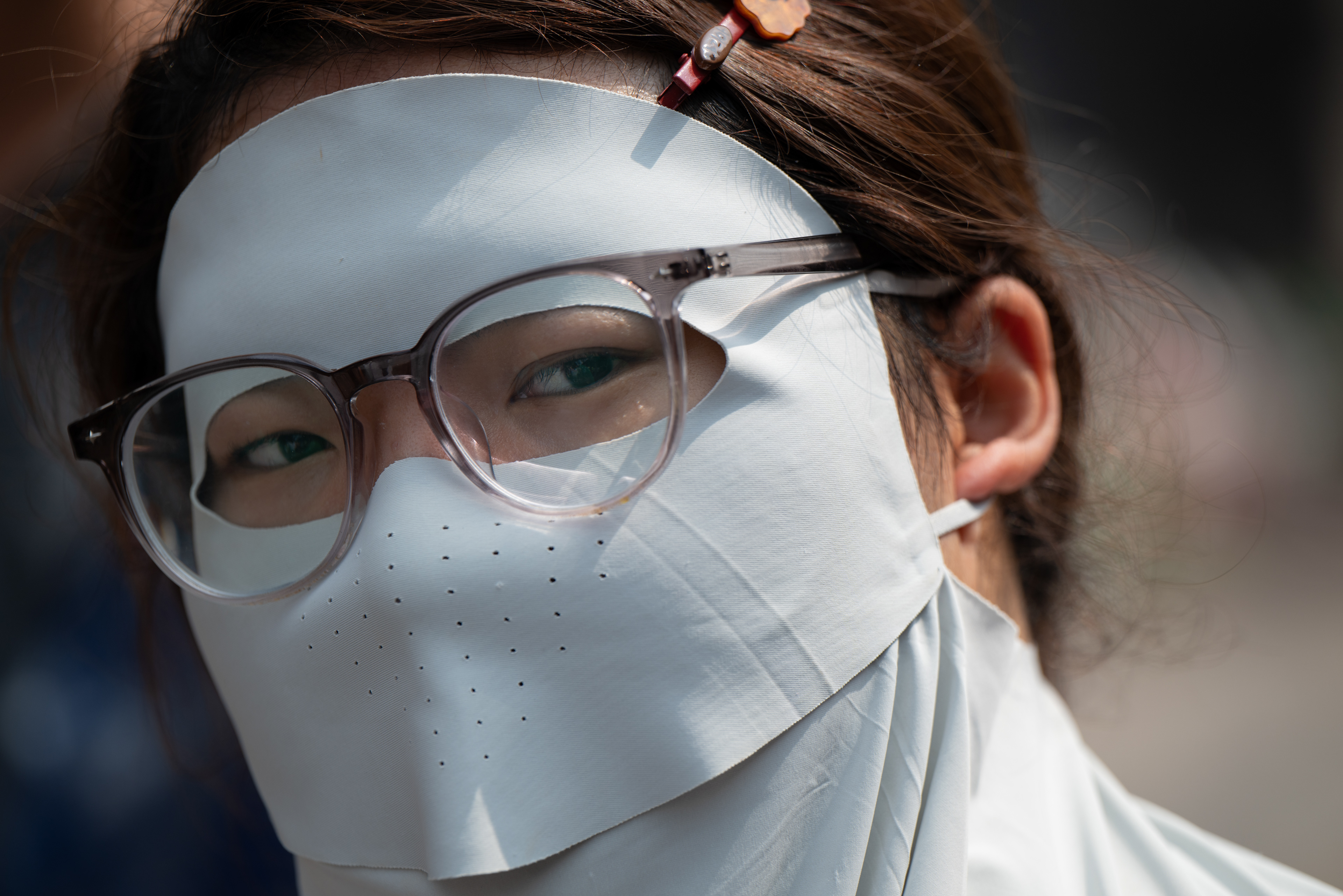 Solo gli occhi – donna con maschera solare bianca e occhiali, di cui si vedono solo gli occhi, Pingyao, Cina