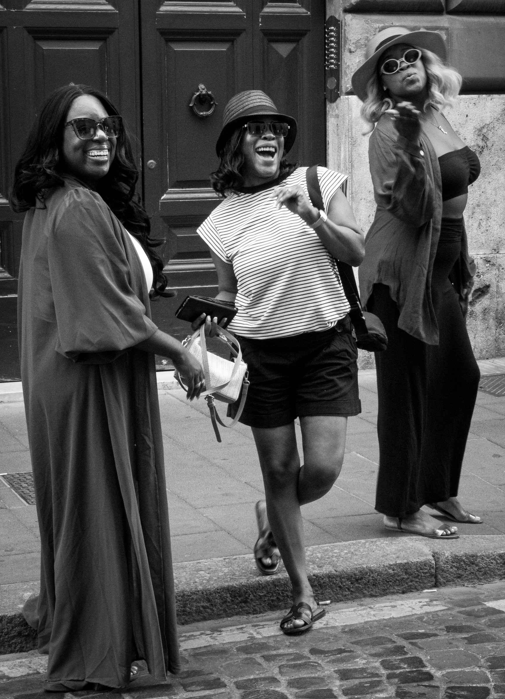 Tre modi di dire ciao – tre donne in una via di Roma salutano il fotografo: una sorride, una ride, una manda un bacio. Fotografia in bianco e nero di Fabio Alimonti.