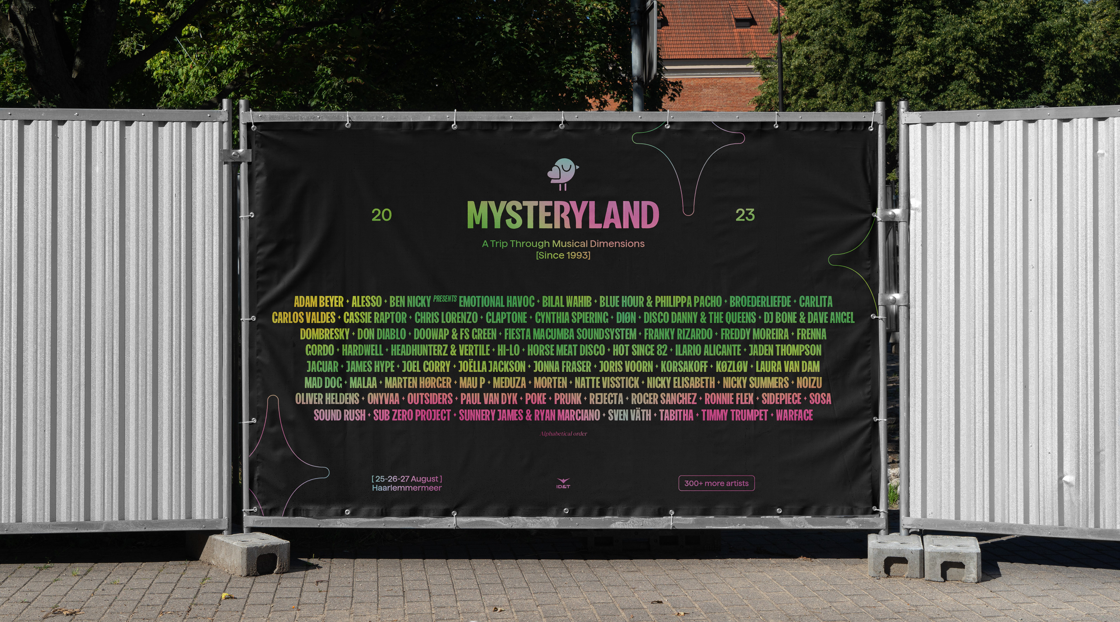 Outdoor banner of Mysteryland festival listing artists, dates, and "A Trip Through Musical Dimensions" slogan.