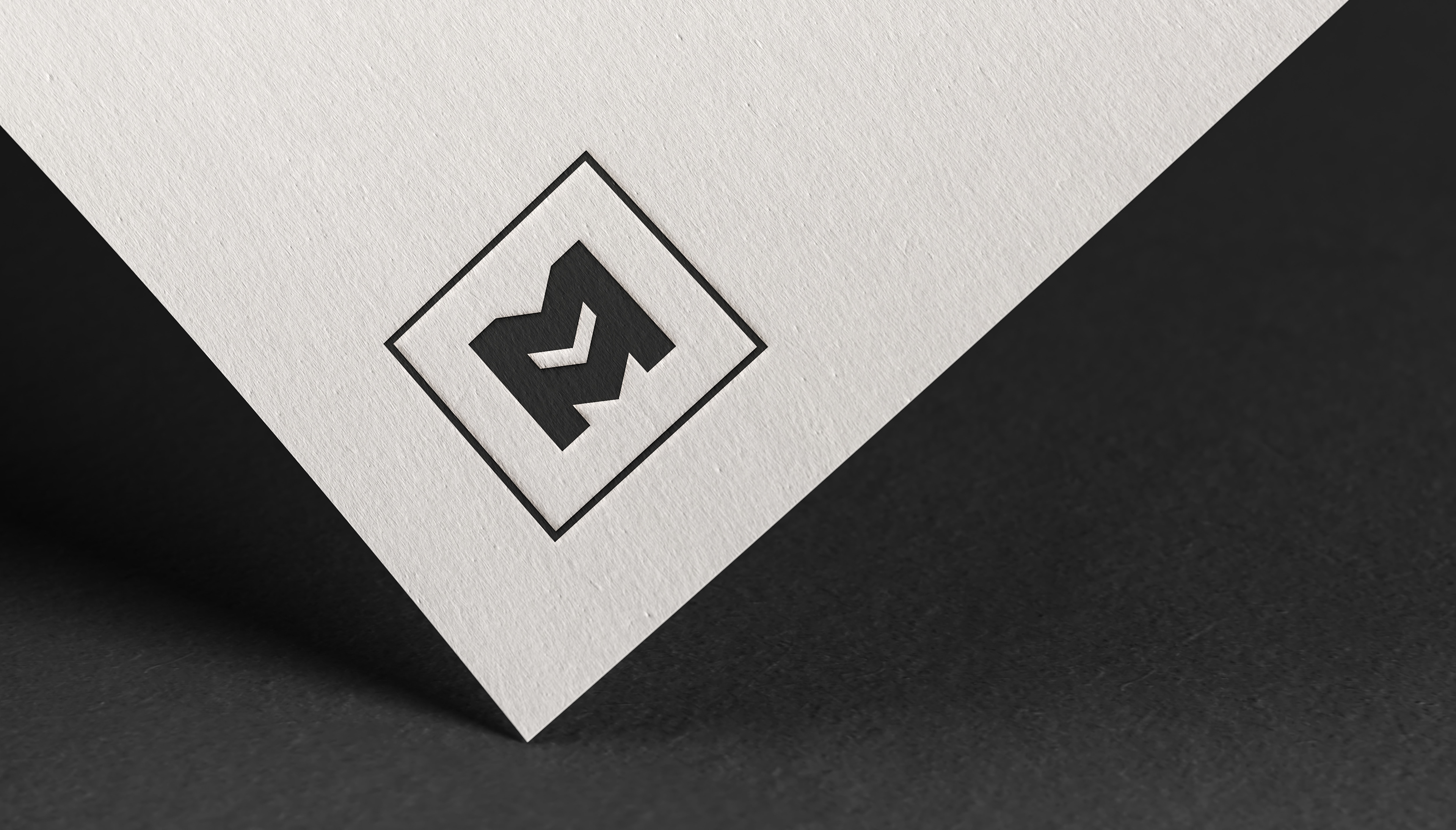 A textured paper with an embossed black geometric logo icon.