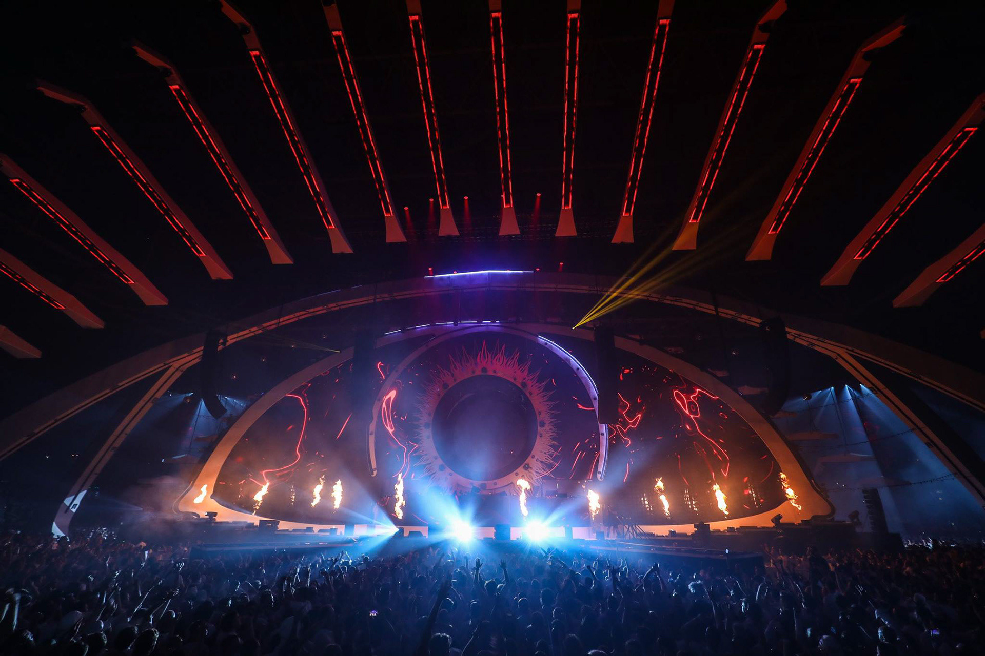 Concert stage with vibrant lights, large crowd, and dynamic pyrotechnics.