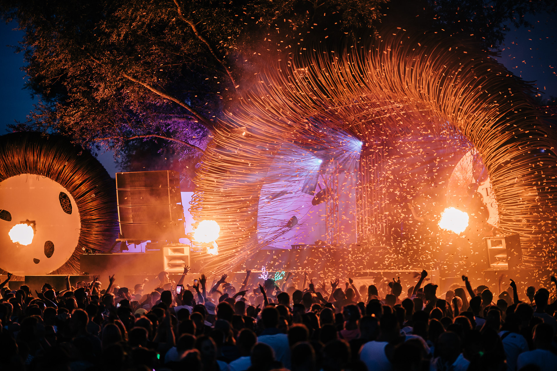 Outdoor festival stage with fireworks and a cheering crowd at night.