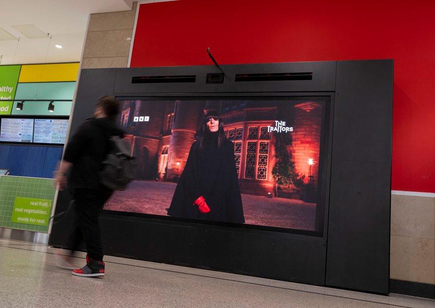 Claudia Winkleman on the promo Video Orbit OOH at Arndale Centre Manchester - in this image a shopper is walking past the screen with motion blur - image was shot by Manchester OOH - mcrooh.com