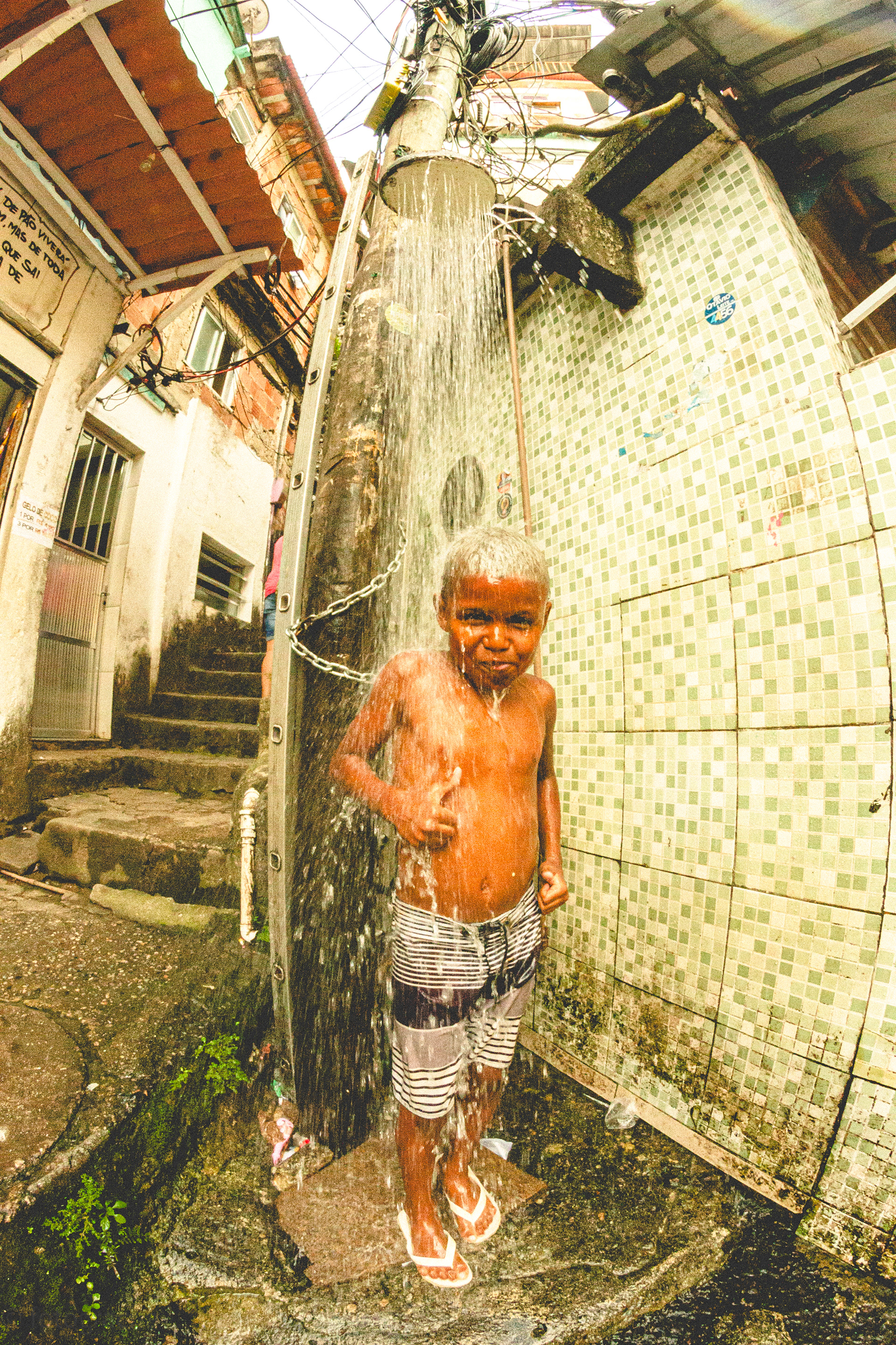 Kauã, filho de Kayode e Ayala, tomando banho de chuveirão no calor do verão na Paula Brito
