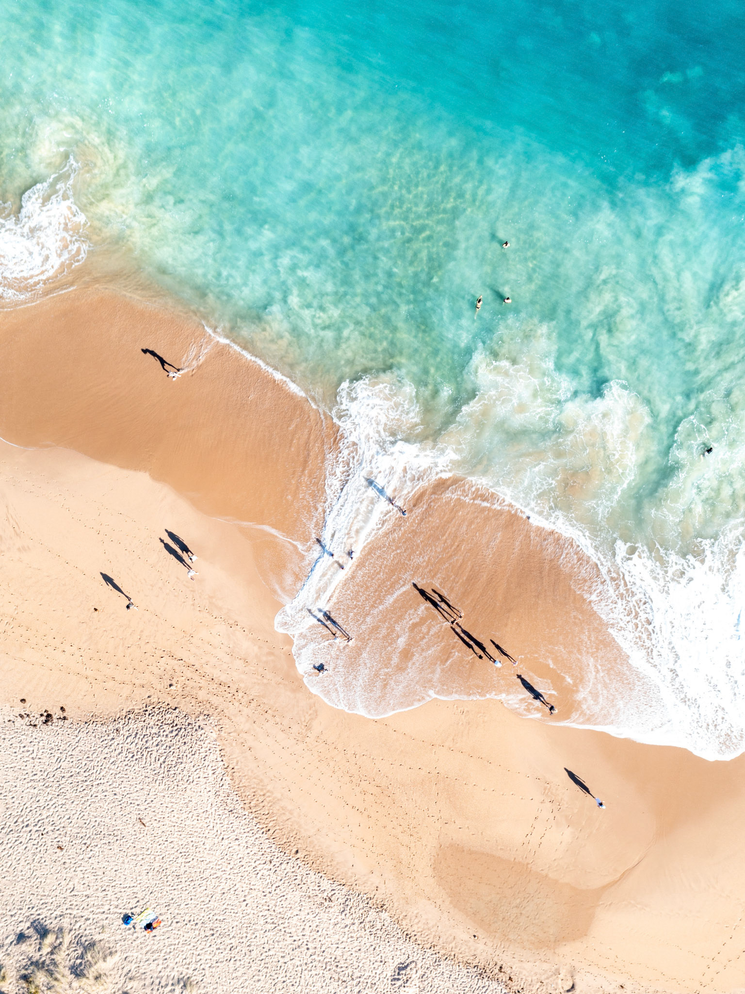 beach goers playing in the waves at boomer beach port elliot south australia