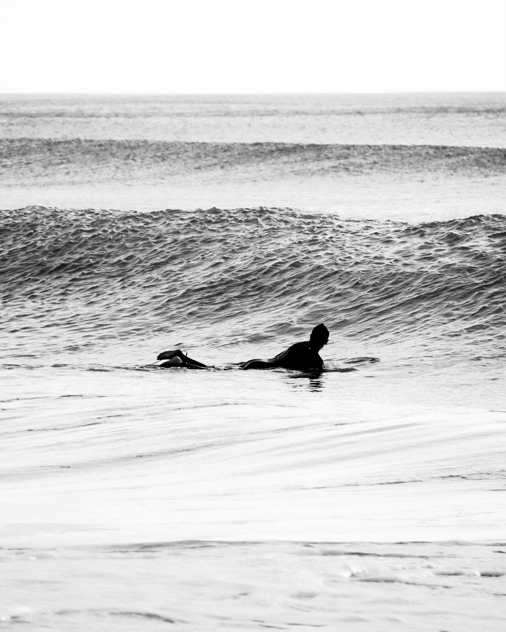 surfer charging ocean waves in black and white