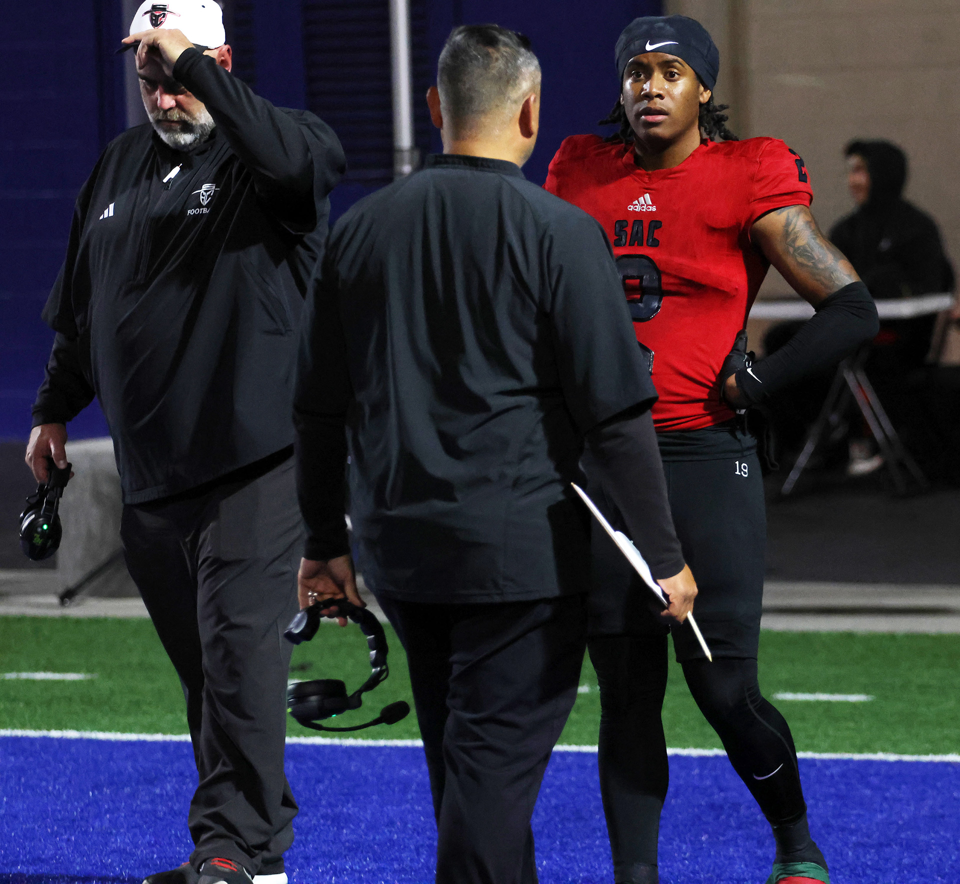 James Famer, a wide reciever for the Dons, is going over the offensive gameplan with the wide reciever coach Simon Fuentes and head coach Geoff Jones (with the white hat) who is seen stressing due to this being the biggest game of the season. 