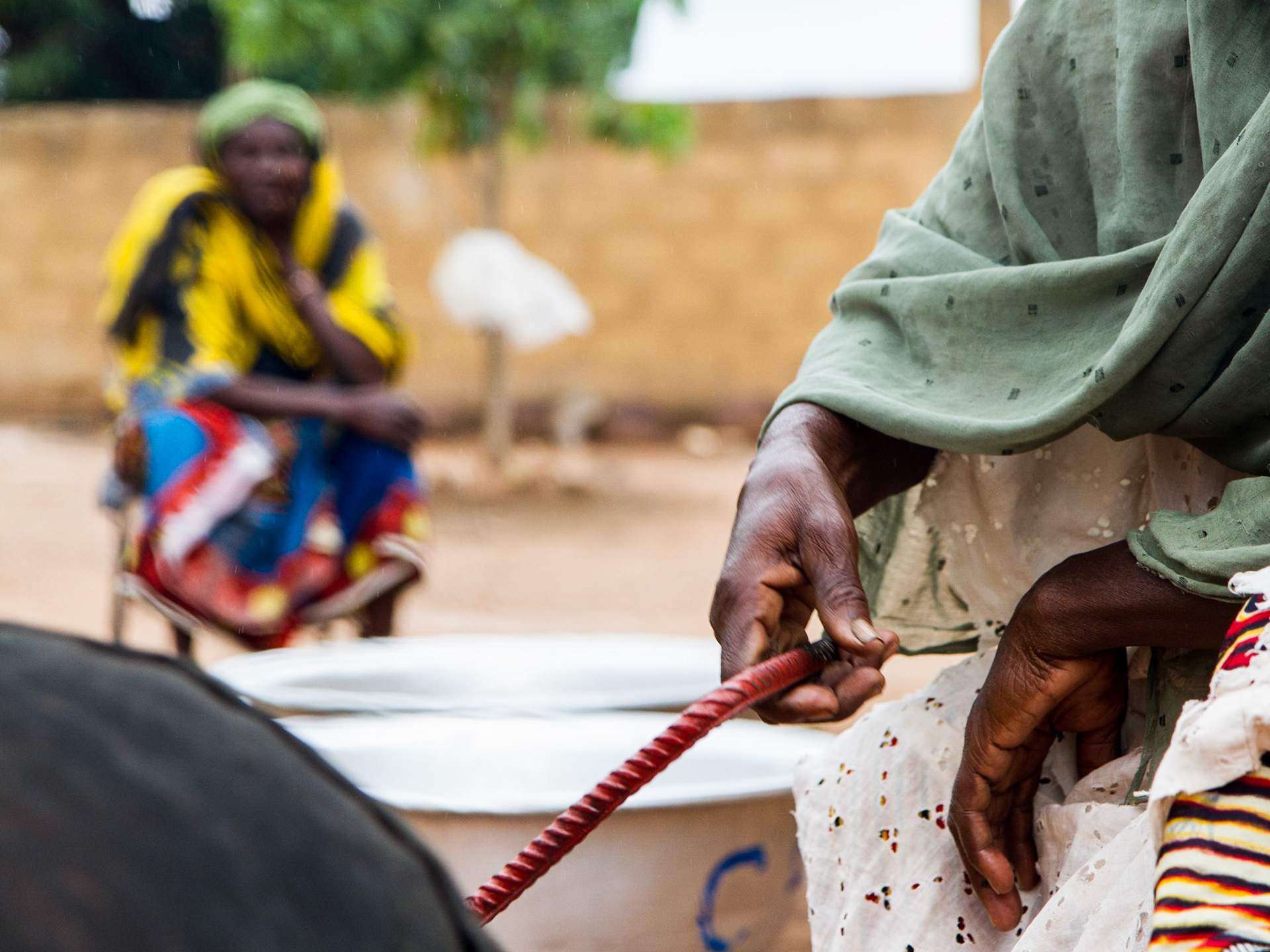 Loulouni, Mali. A woman turns a barrel filled with peanuts over a fire as another looks on. Taken July 4, 2012.
