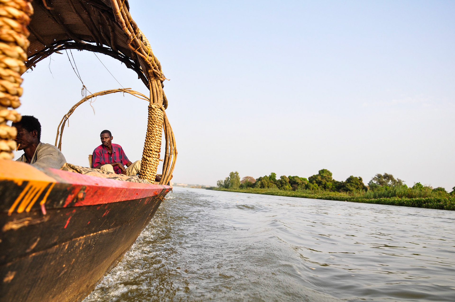 Niamey, Niger. A long boat speeds past green vegetaion on the Niger's banks. Taken February 16, 2011.