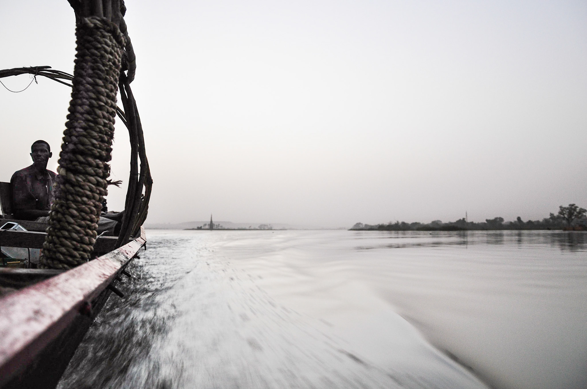 Niamey, Niger. A long boat cuts through a calm Niger River at dusk.  Taken February 16, 2011.