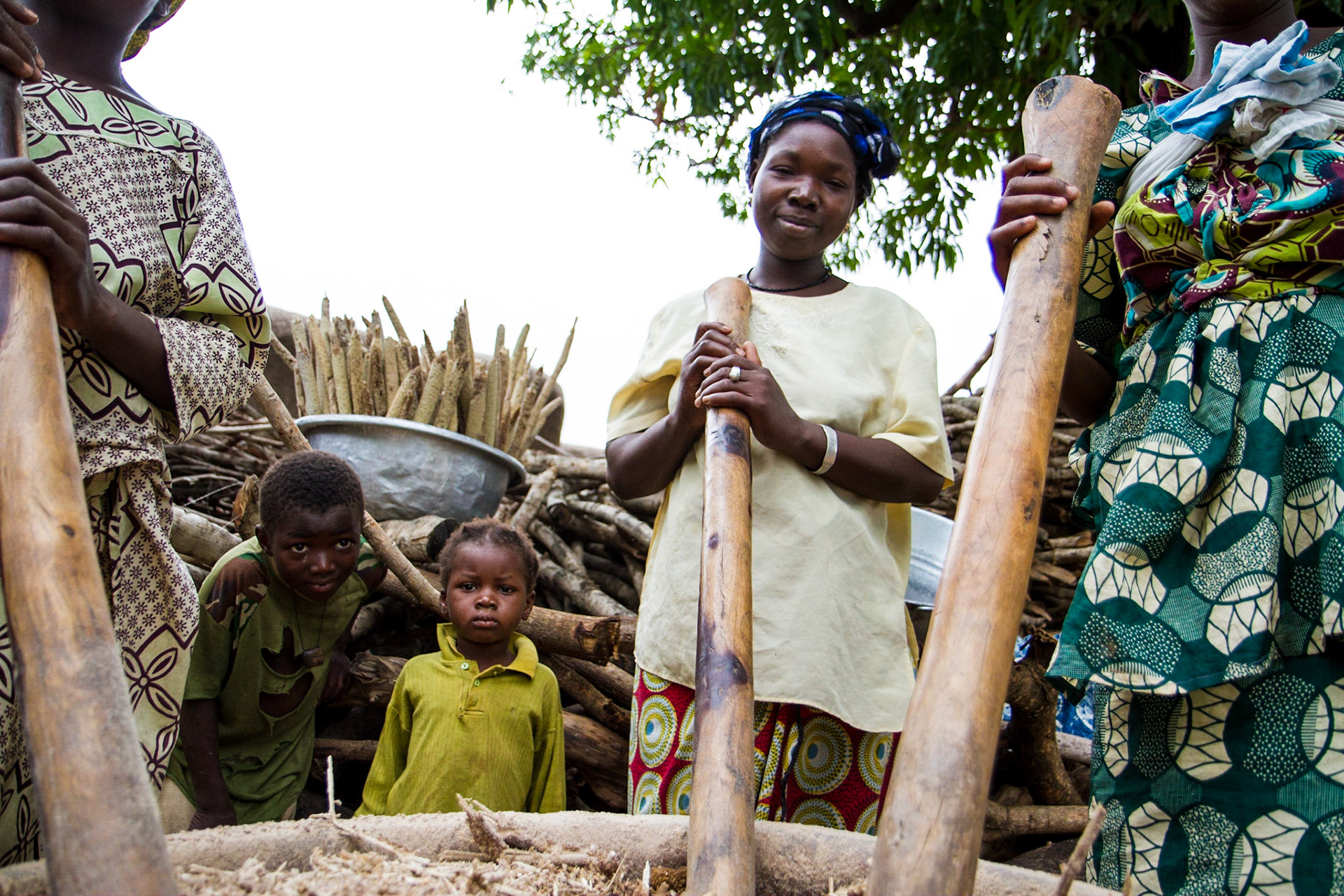 Molobala, Mali. Young women take a break from pounding millet with a large mortar and pestle. Taken July 2, 2012.