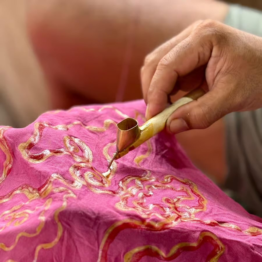 Wax being applied to dyed fabric using a tjanting tool