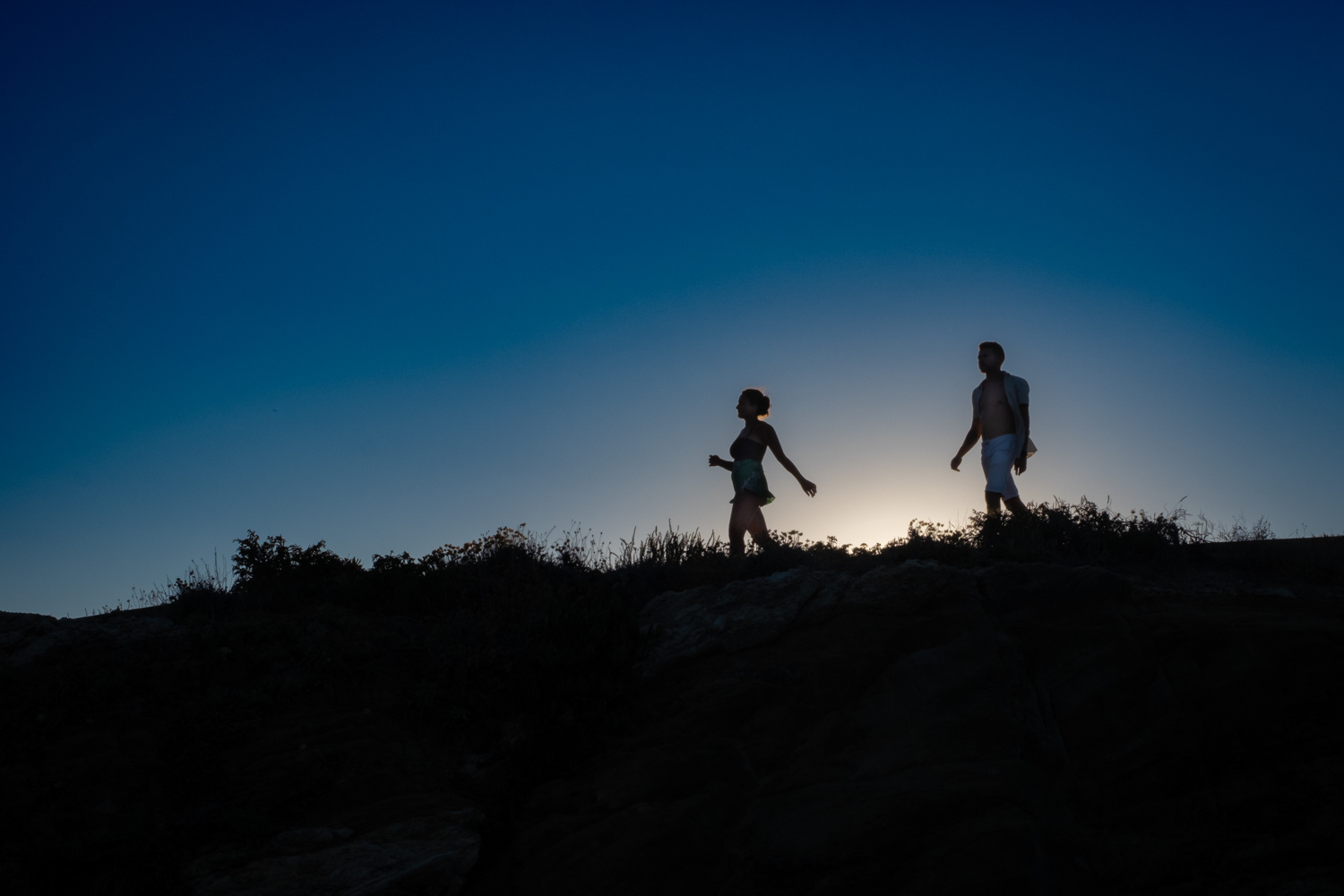 A summer image. A woman and a man on silhouettes walking in the sunset