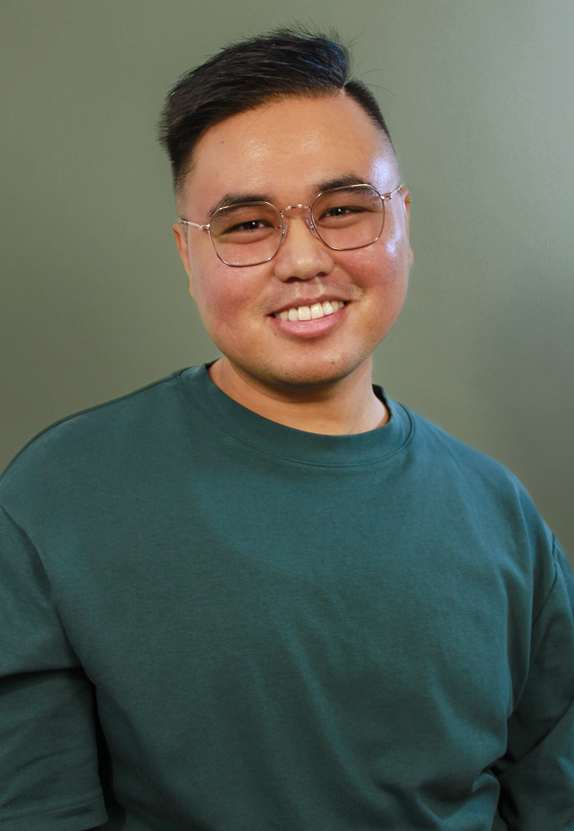 Headshot of Matt Lescano smiling, wearing a green shirt on a forest green backdrop.