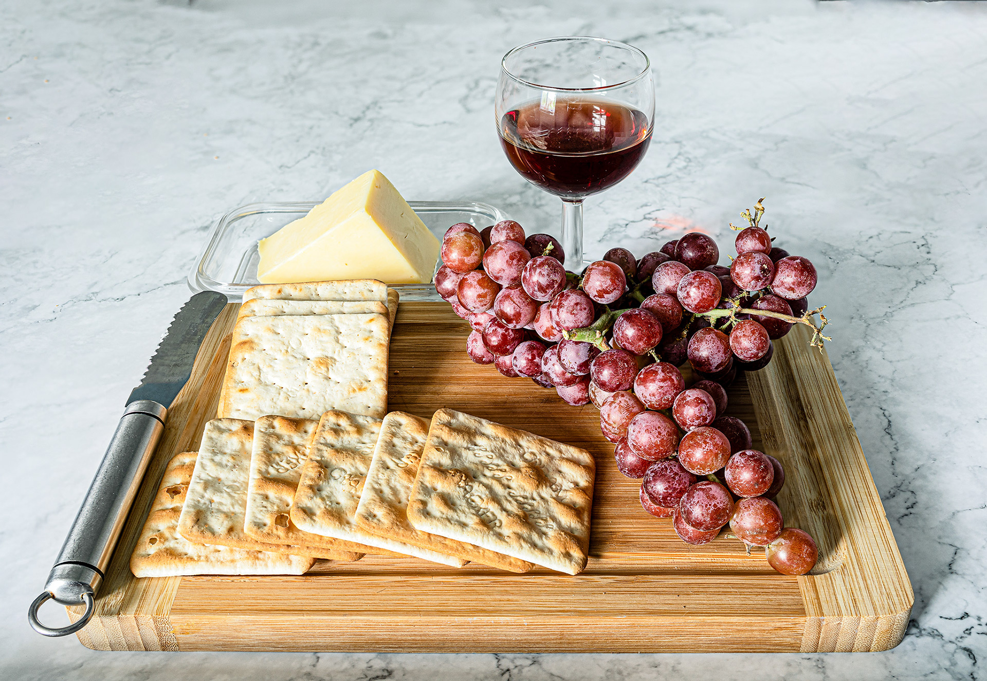 a cheese board with grapes and wine