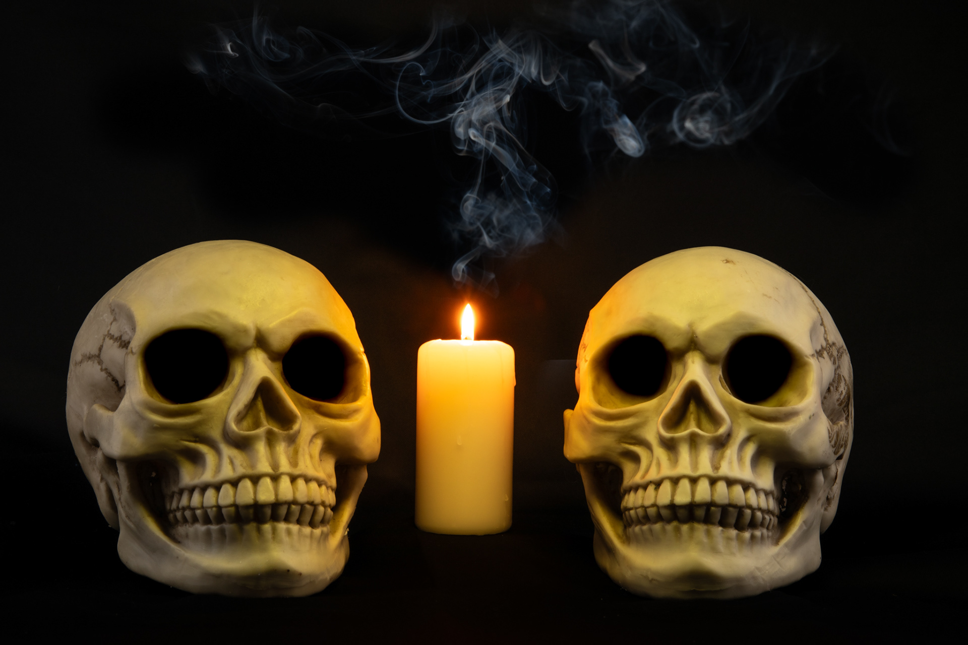 2 human skulls with a candle