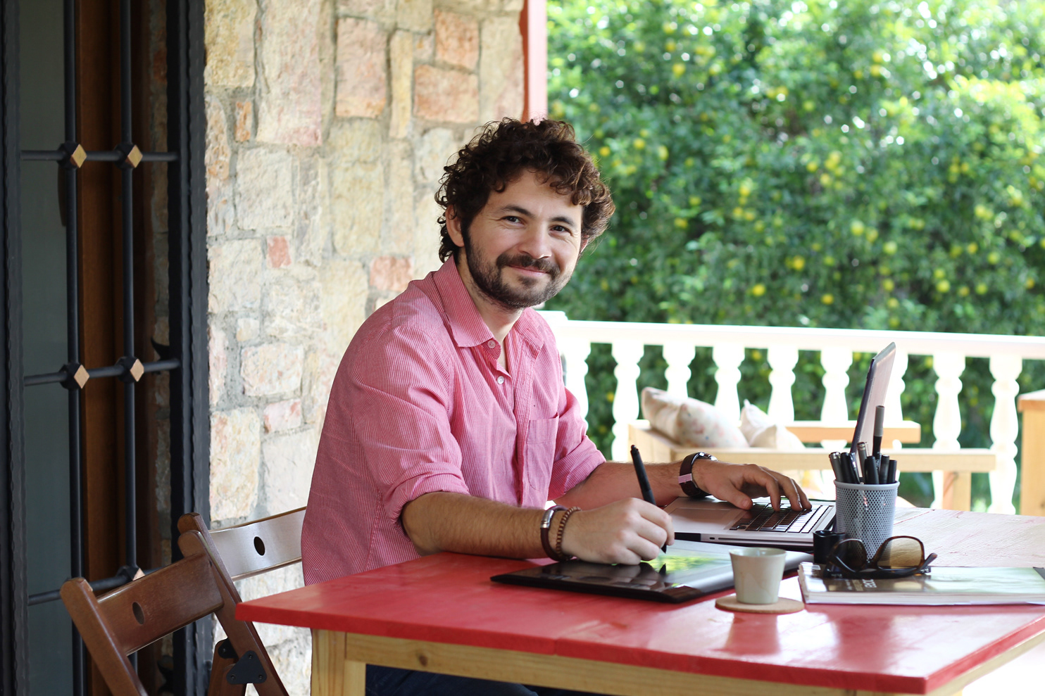 Illustrator Kürşat Ünsal drawing on a graphics tablet at his desk in Bodrum