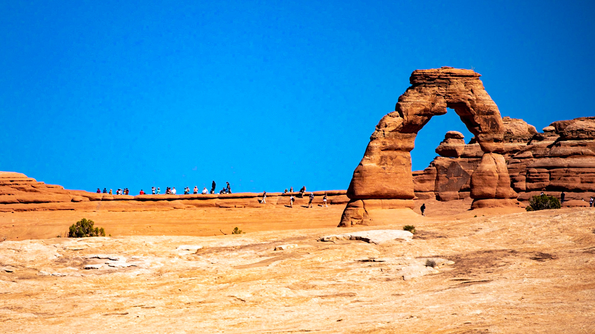 The symbol of Utah, Delicate Arch, Arches NP., taken from a mile away.  Handy humans added for scale.