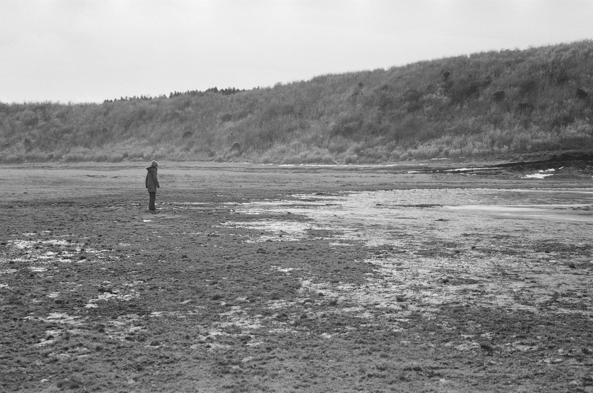 K - image of my mother visiting a place where she used to ice skate as a little girl, its is now a muddy pond