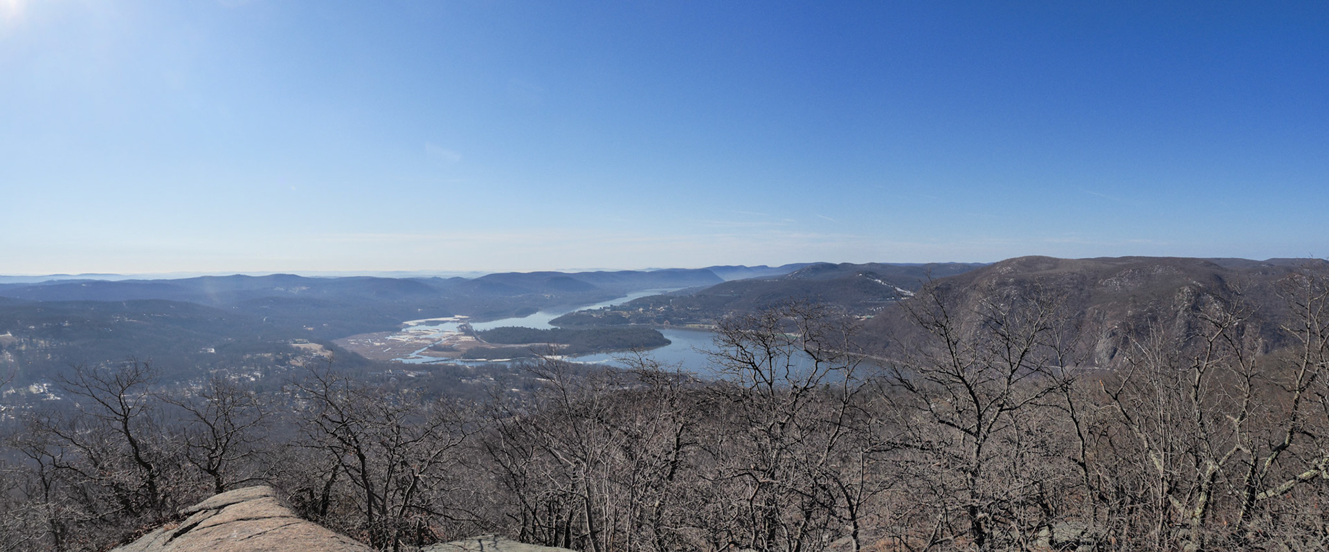 It's a clear day and in that haze is a city view. West Point and Bear Mountain in the background.