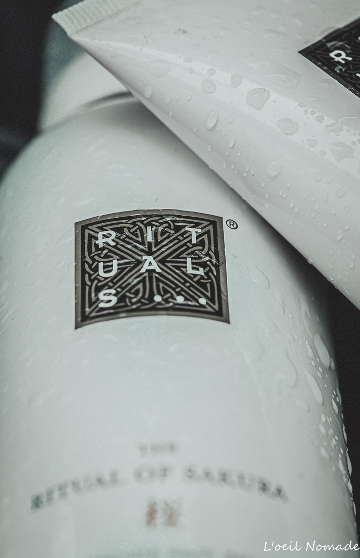 Gros plan texture tube Rituals of Sakura, gouttes d'eau et mise en avant du logo, style épuré.