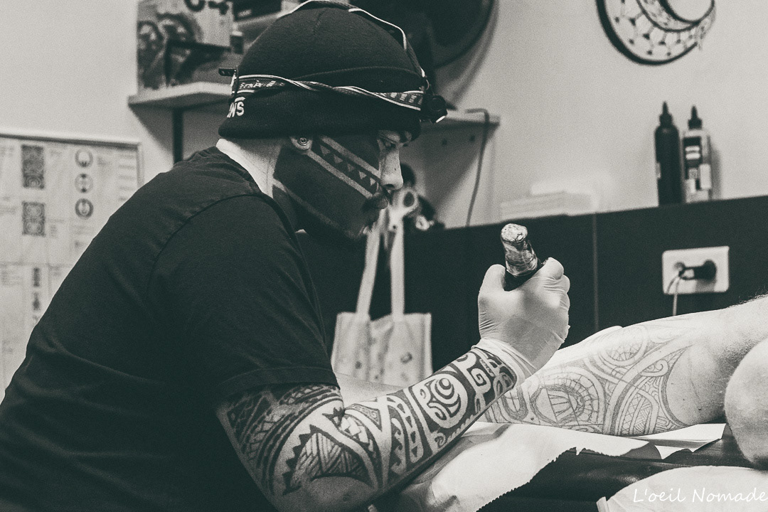 Photographie documentaire de tatouage au Havre : portrait serré d'un tatoueur en pleine création, focus sur la concentration et l'expertise du geste technique.