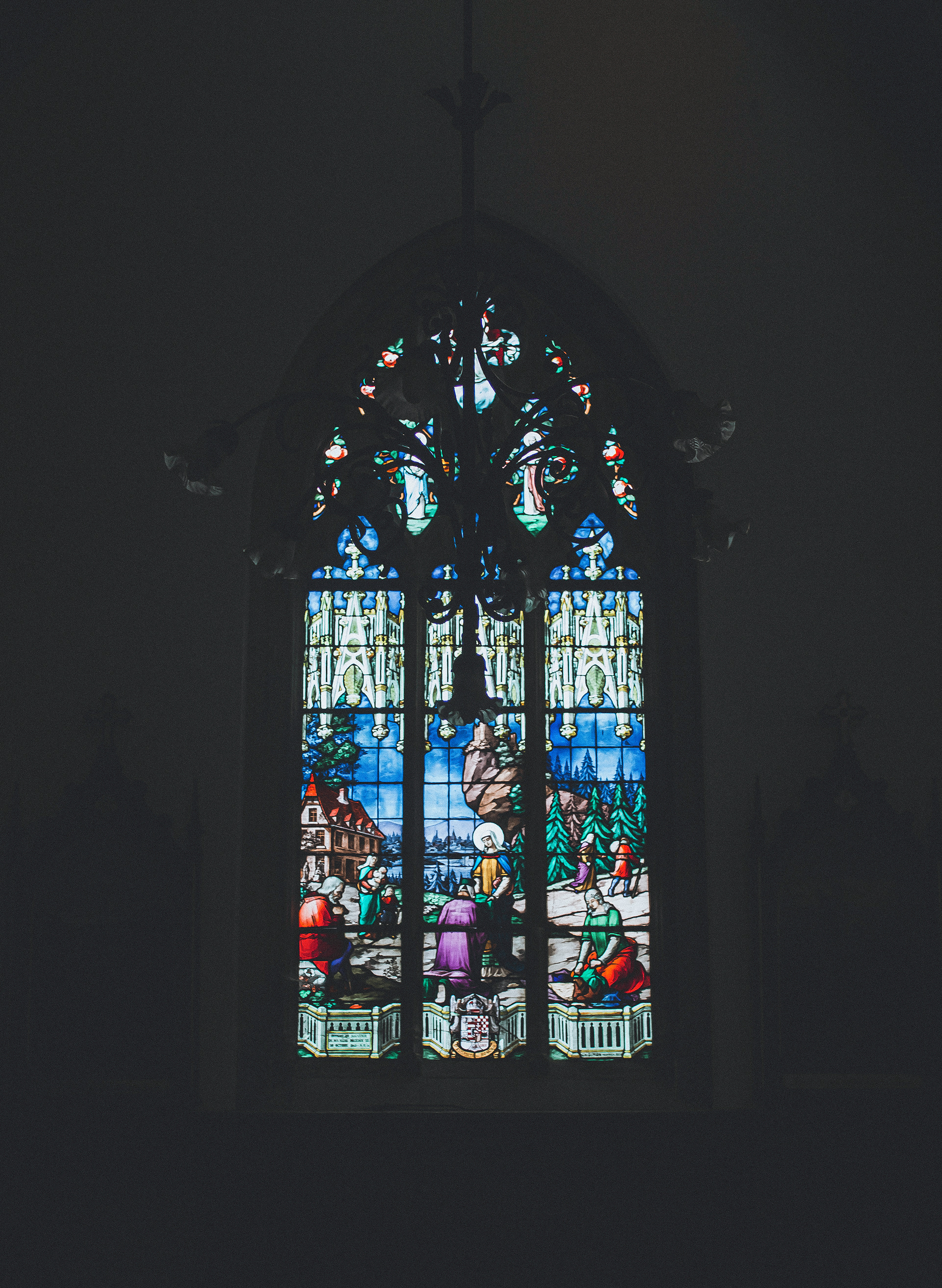 Photographie de détail : vitrail gothique coloré illustrant des scènes religieuses dans l'église de Fécamp.