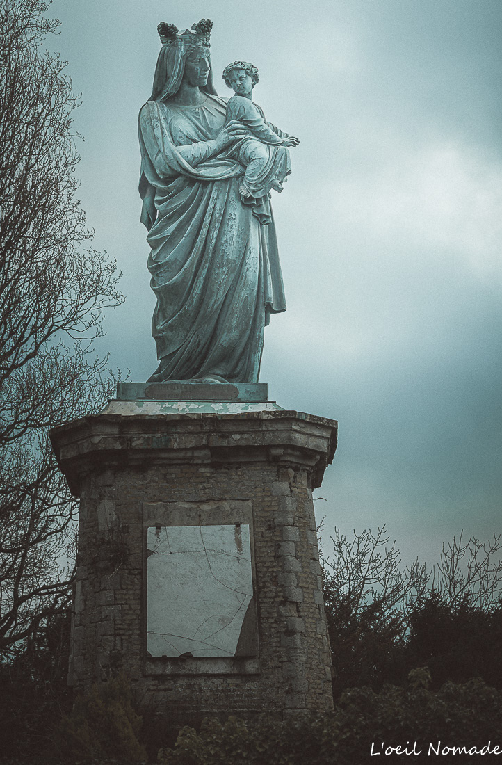 Statue religieuse ancienne Abbaye de Graville, détails de la pierre érodée et lichens, style Dark Muted.