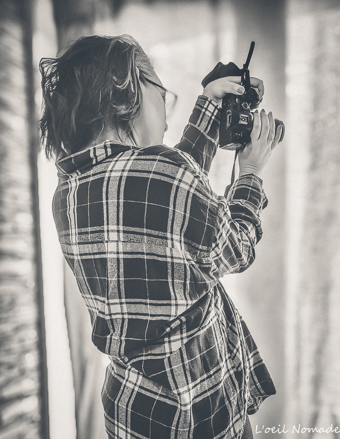 Photographe professionnelle en pleine prise de vue, appareil en main, illustrant l’expertise, la rigueur et la valeur du travail photographique.