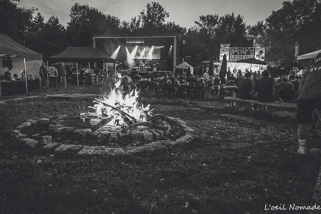 Reportage événementiel : foule et feu de camp nocturne, maîtrise de la lumière naturelle et de l'ambiance collective.