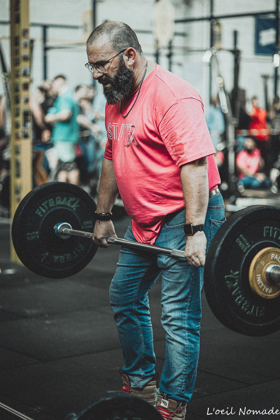 Reportage coulisses CrossFit : organisateur préparant le matériel, valorisation de l'ombre et de l'effort logistique derrière l'événement sportif.