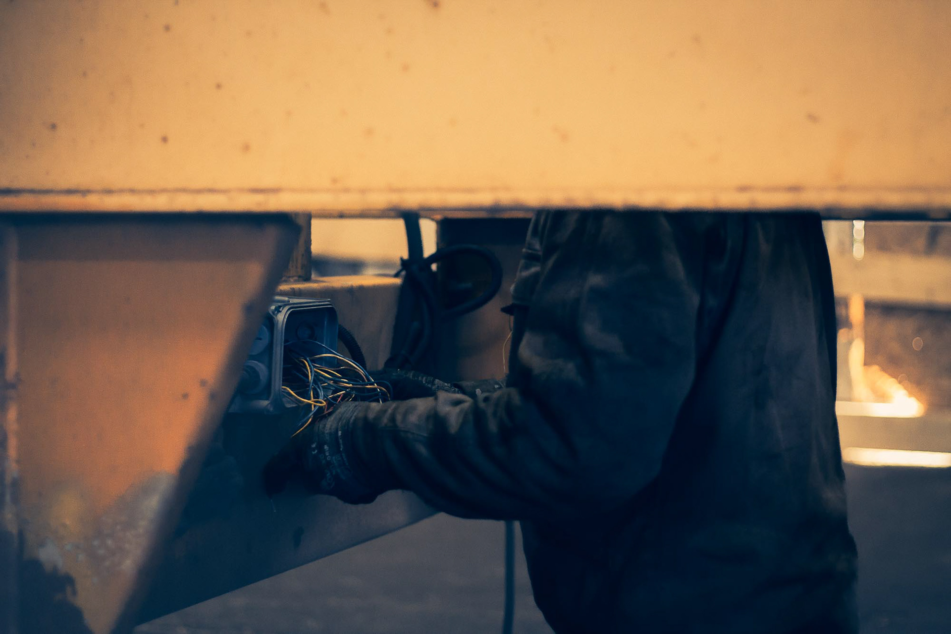 Reportage photo industriel : technicien Jeletrans intervenant sous un châssis de poids lourd, captation de la difficulté technique et de l'environnement de maintenance.