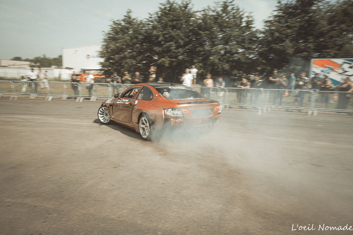 Voiture de drift en action sur une piste extérieure lors d'un spectacle mécanique.