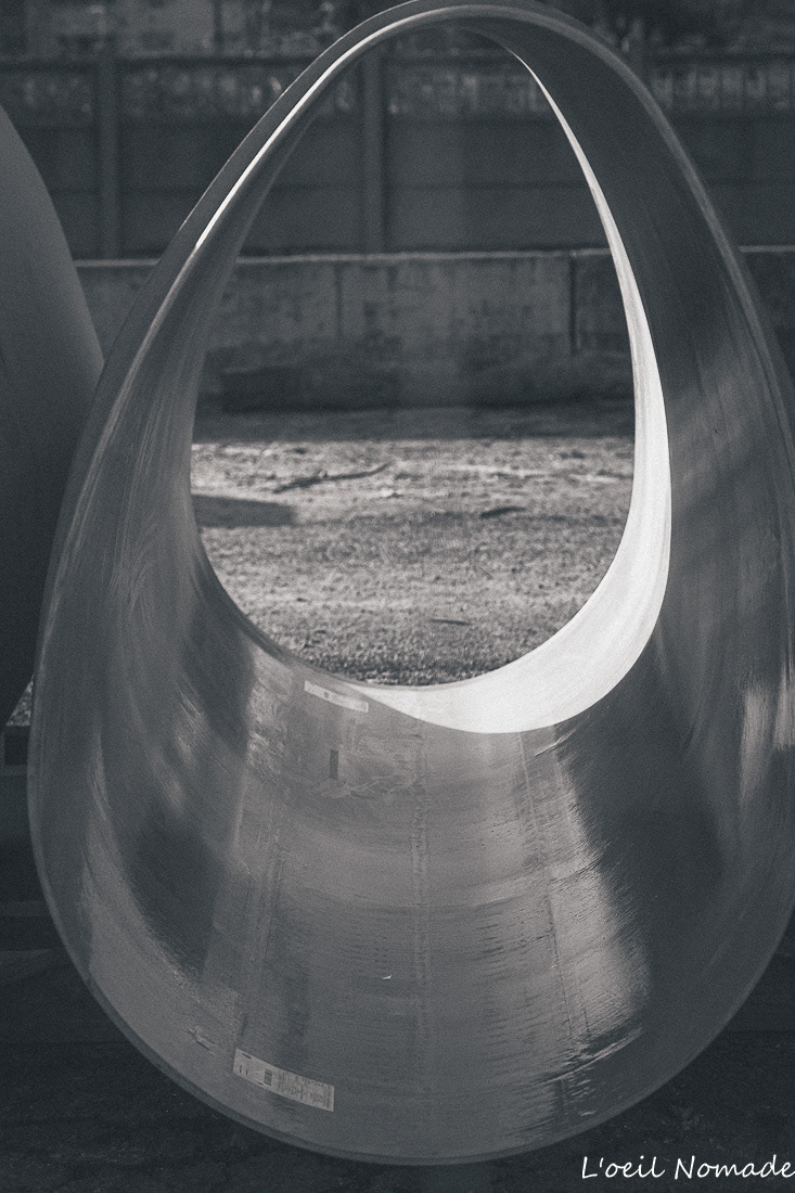 Vue artistique à travers une canalisation de chantier, jeux de lumière et de géométrie sur les infrastructures urbaines.