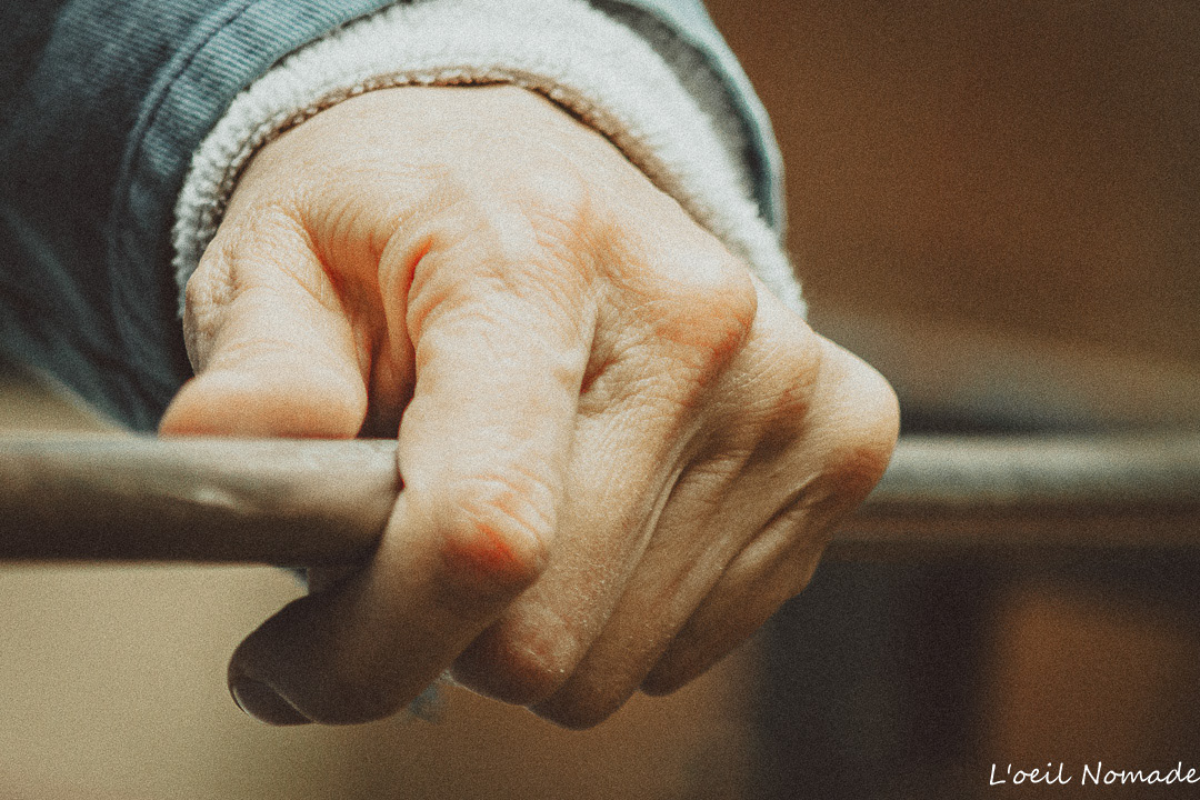 Photographie documentaire d'artisanat au Havre : gros plan sur la main d'une souffleuse de verre tenant sa canne de travail, témoignage du savoir-faire et du lien à la matière.
