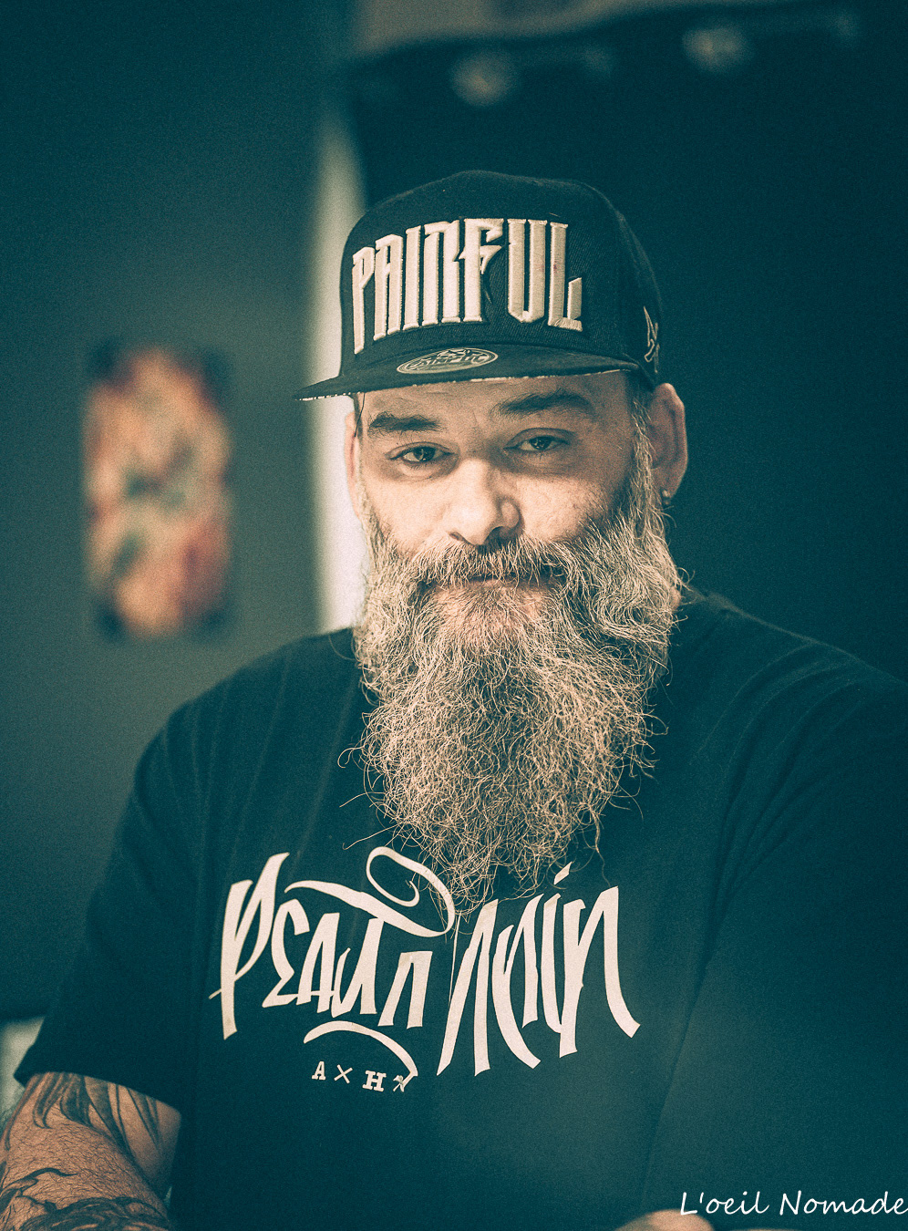 Portrait d'homme barbu casquette Painful, regard direct et assuré dans une ombre habitée, photographie d'autorité authentique.
