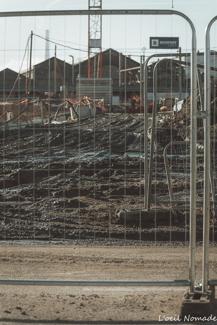 Focus sur les barrières de protection et le périmètre de sécurité d'un chantier urbain en journée.