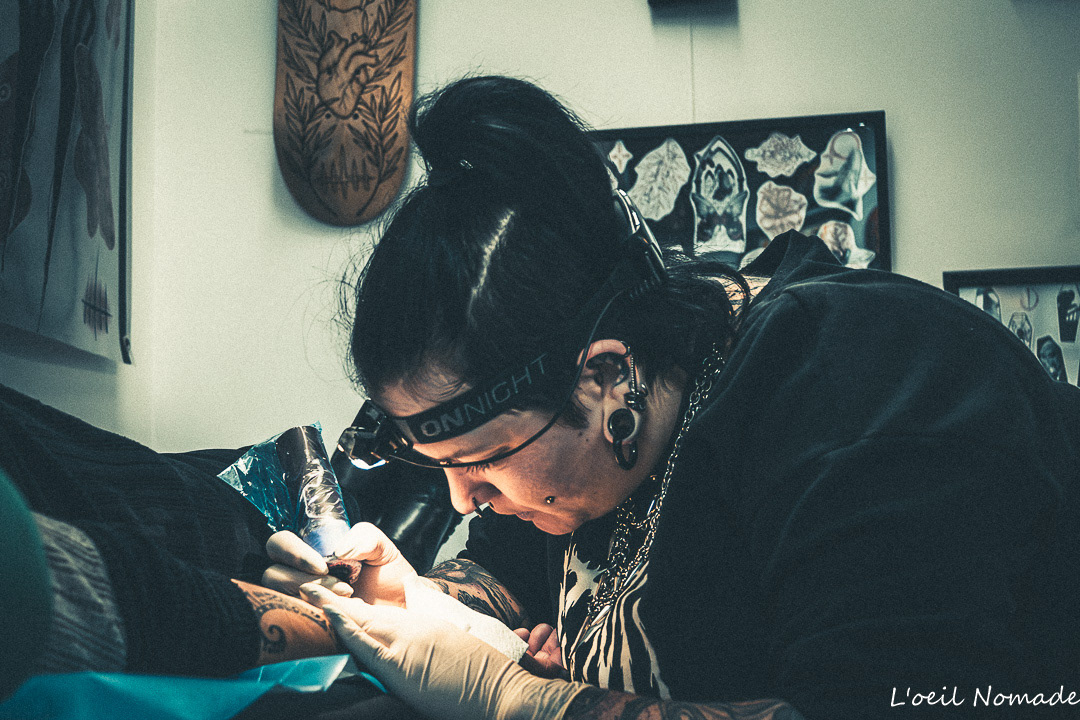 Reportage métier chez Frank Tatouage : la tatoueuse Lamnu en pleine séance de création, captation du geste précis et de l'ambiance authentique du shop.