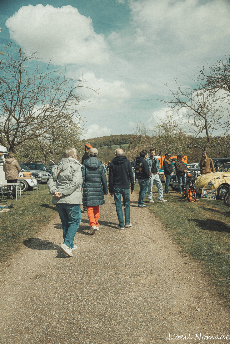 Participants lors d'un rassemblement automobile en Normandie photographiés dans une approche documentaire centrée sur les échanges humains.