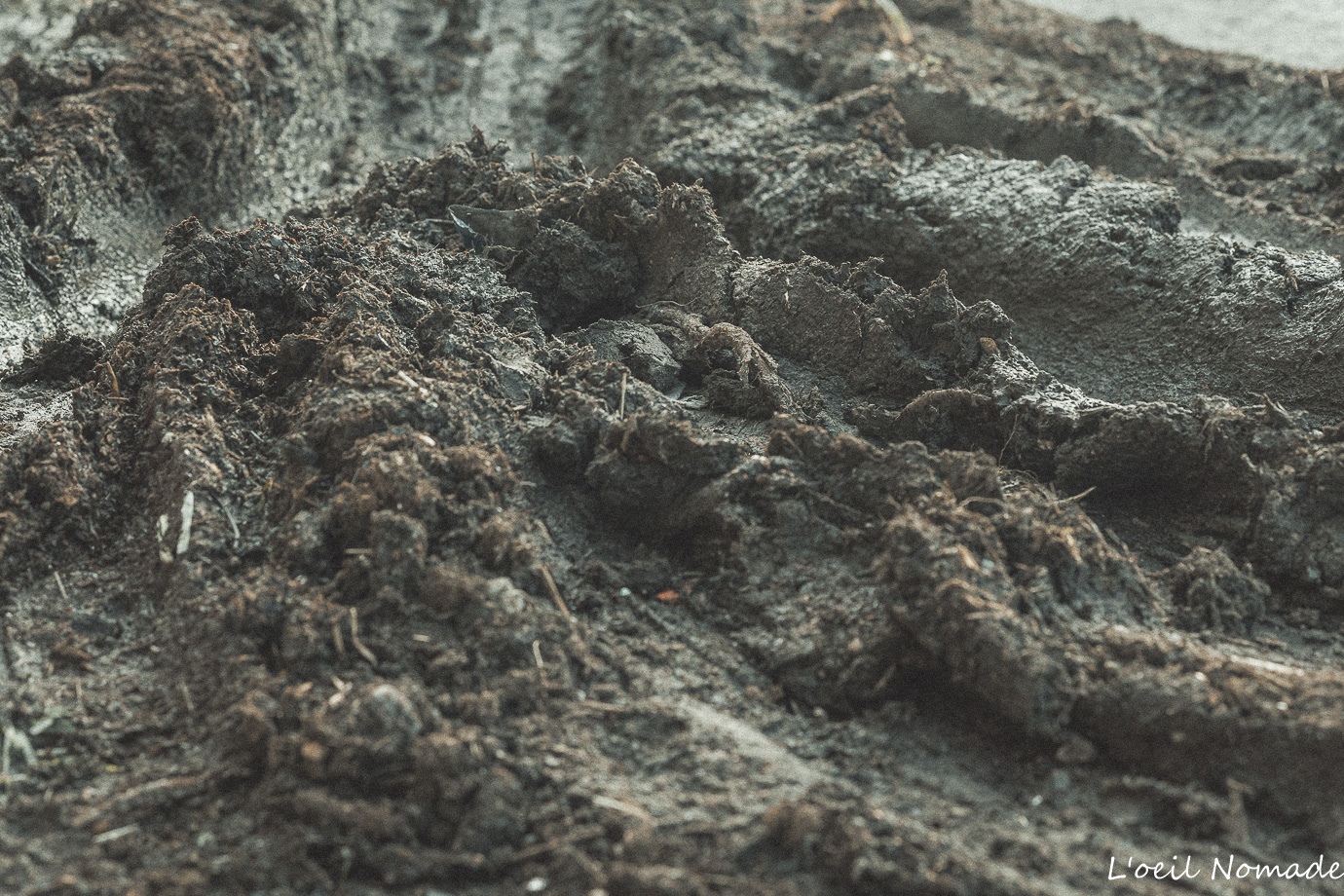 Texture brute de terre et déblais de chantier, photographie de terrain en lumière naturelle, esthétique documentaire sombre.