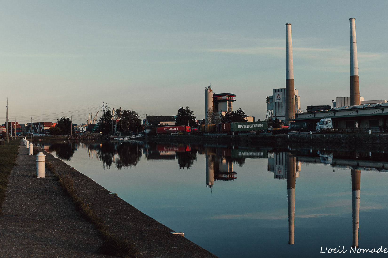 Cheminées industrielles visibles depuis les quais du Havre au coucher du soleil.