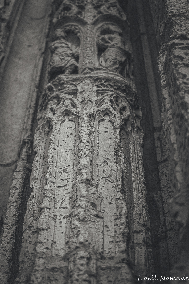 Gros plan sur une sculpture en pierre rongée par le temps, Rouen, focus sur la matière et la patine.