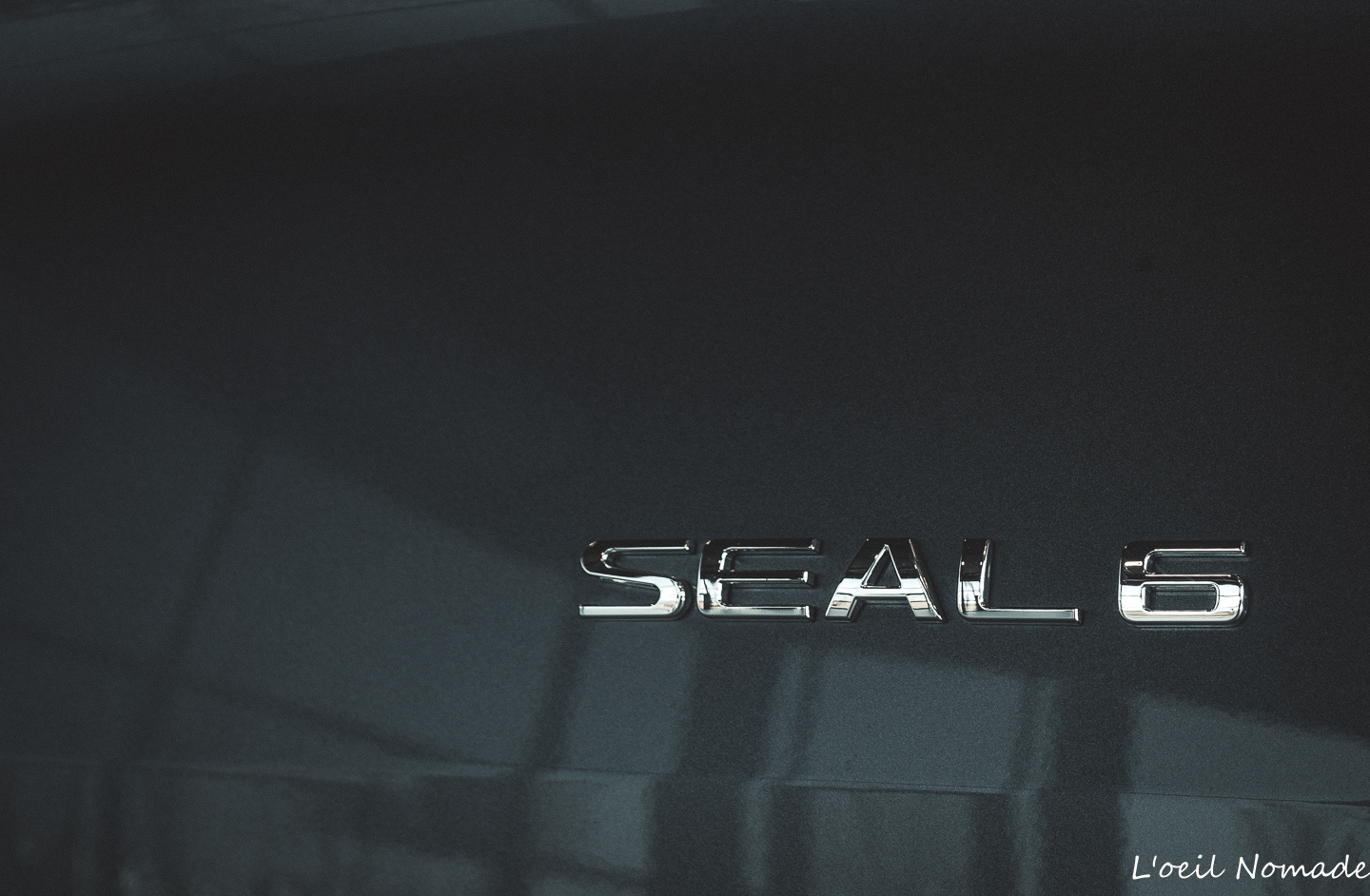 Détail de carrosserie automobile BYD SEAL avec logo moderne, innovation électrique et aérodynamisme.