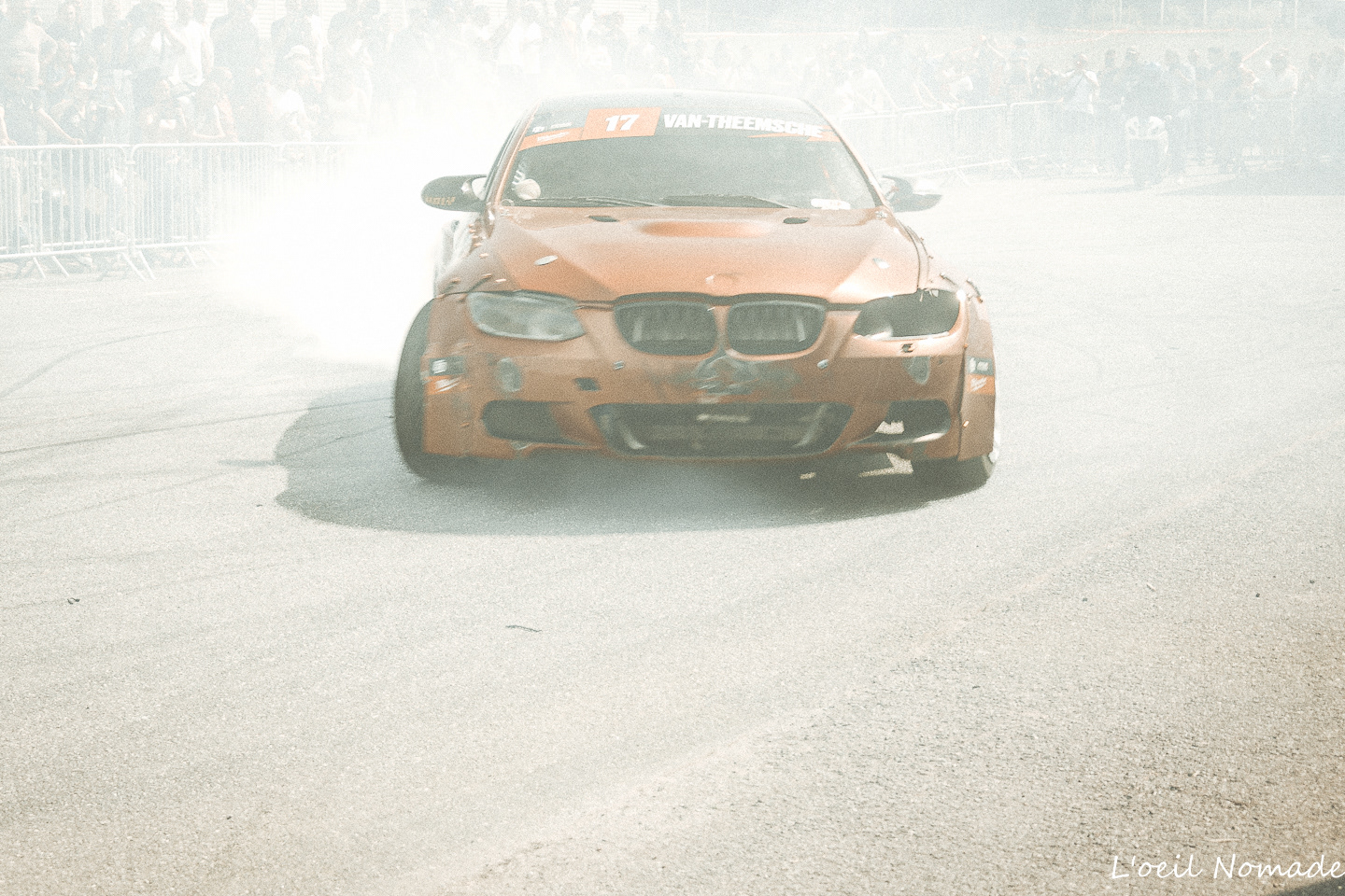BMW de drift avançant dans un nuage de fumée pendant une démonstration automobile.
